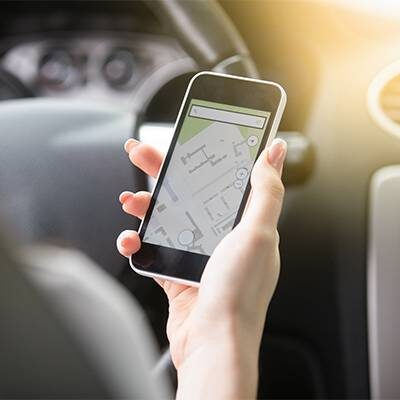 Close up of traveler female hand holding her phone with navigation system. Young woman traveling by car, trying to find the shortest route to a certain destination